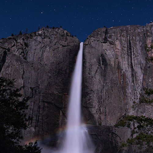A moonbow occurs when light from the moon refracts in the mist from a roaring waterfall.
